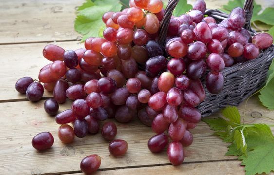 Red grapes in braided basket on wooden table